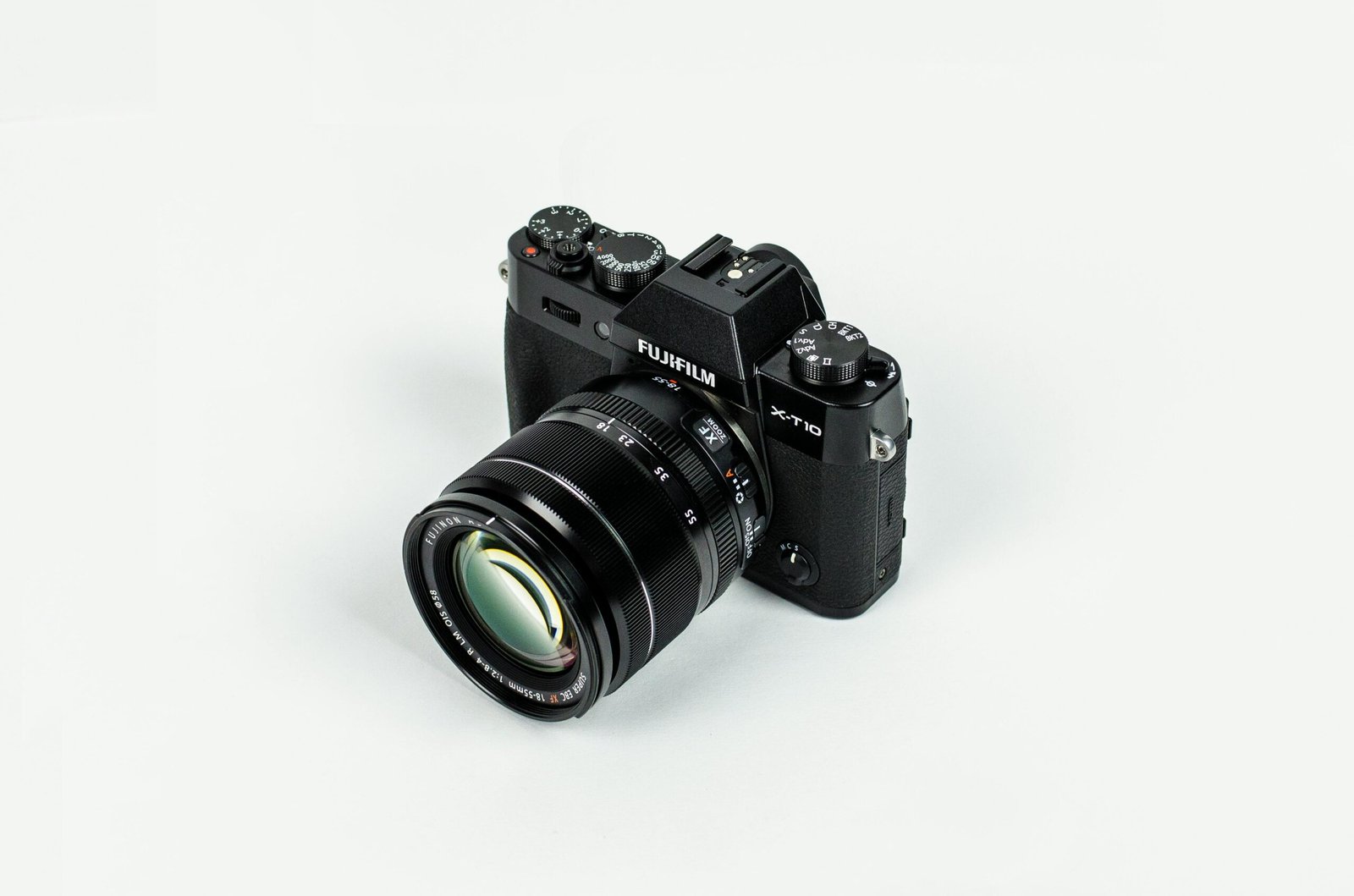 Close-up of a Fujifilm camera with lens on a plain background, showcasing photographic equipment.